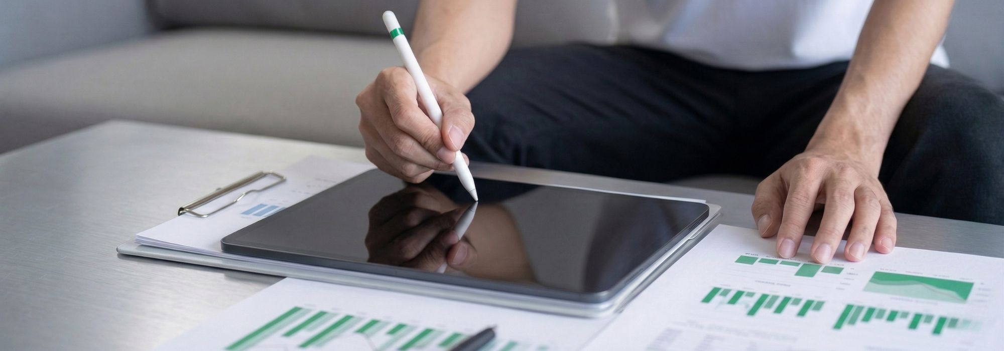 Ingenieur mit Tablet und Zetteln mit Diagrammen am Tisch